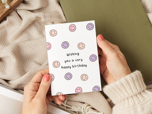 Birthday card which reads 'wishing you a very happy birthday' with lots of smiley faces.