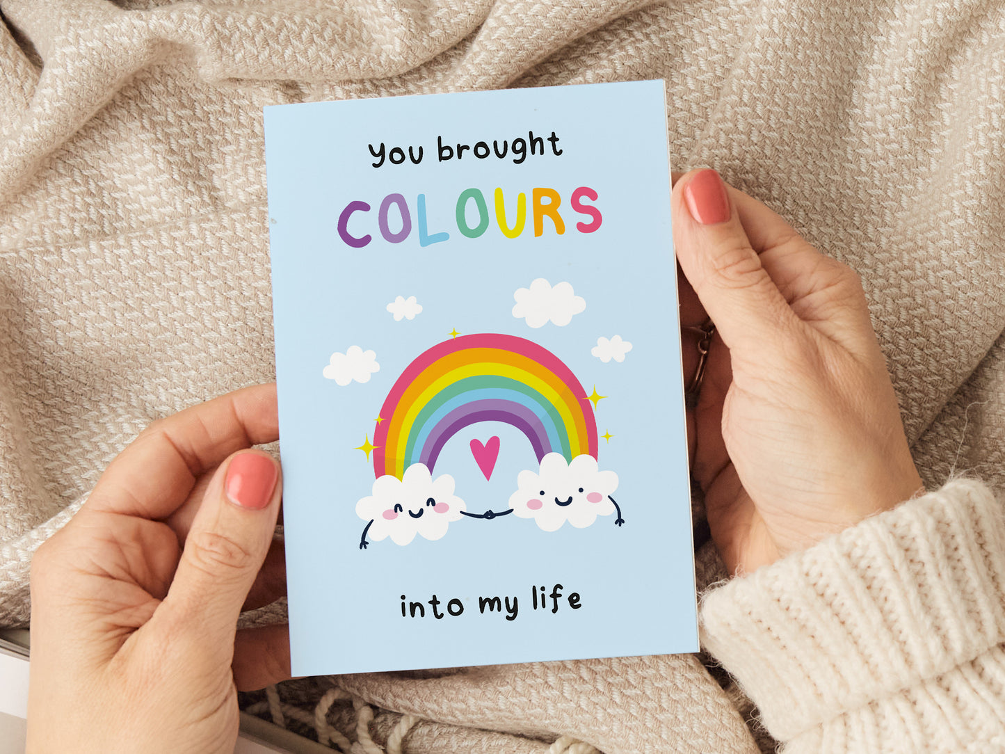 Greeting card which reads 'you brought colours into my life' with an illustration of two clouds holding hands and a rainbow.