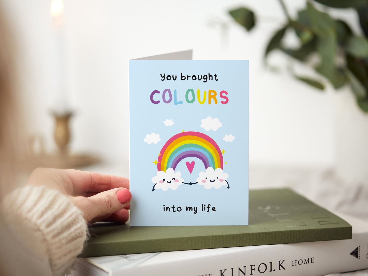 Greeting card which reads 'you brought colours into my life' with an illustration of two clouds holding hands and a rainbow.