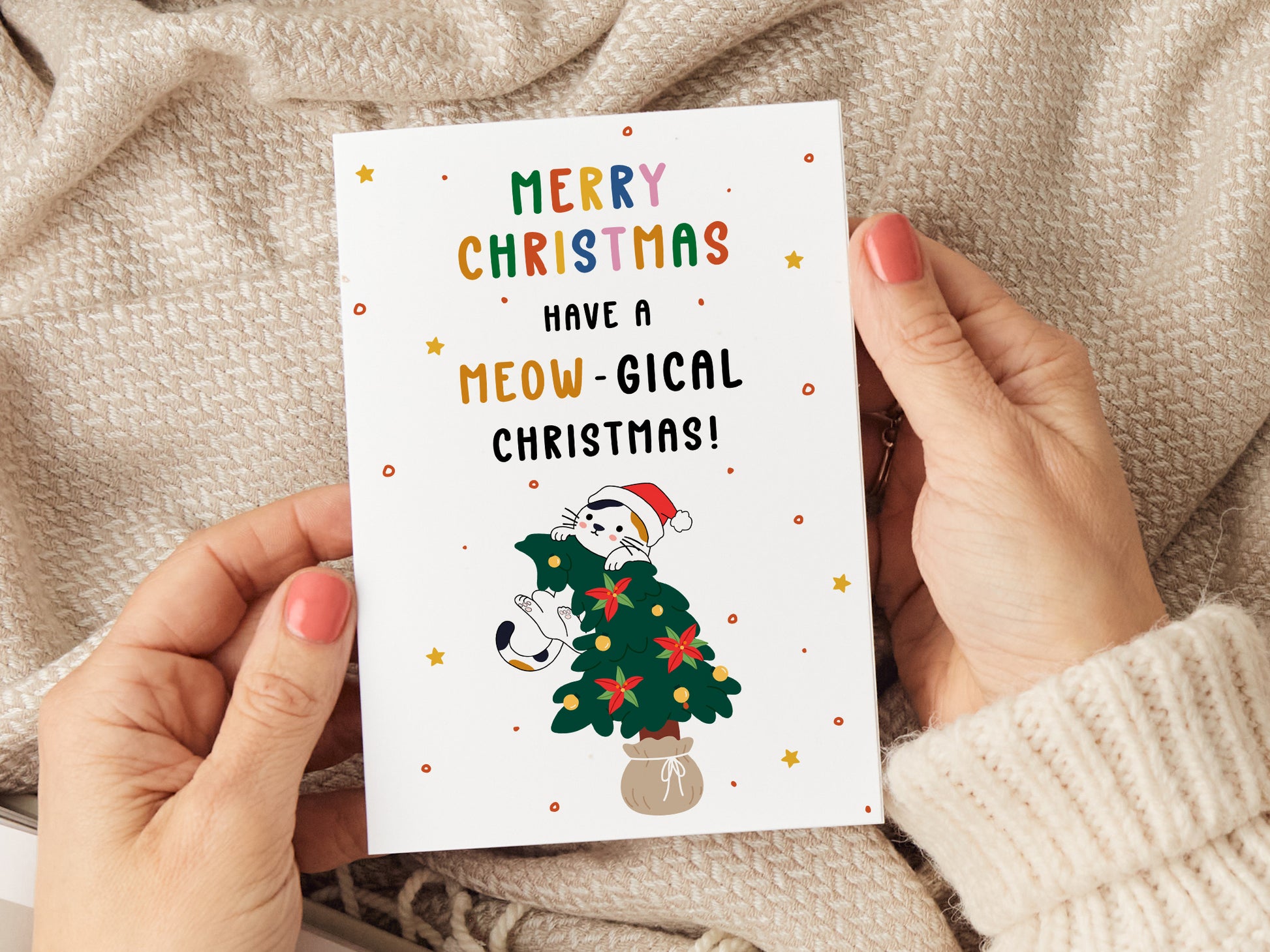 Christmas card which reads 'merry christmas have a meow-gical christmas' with a cartoon illustration of a cat jumping on a christmas tree.