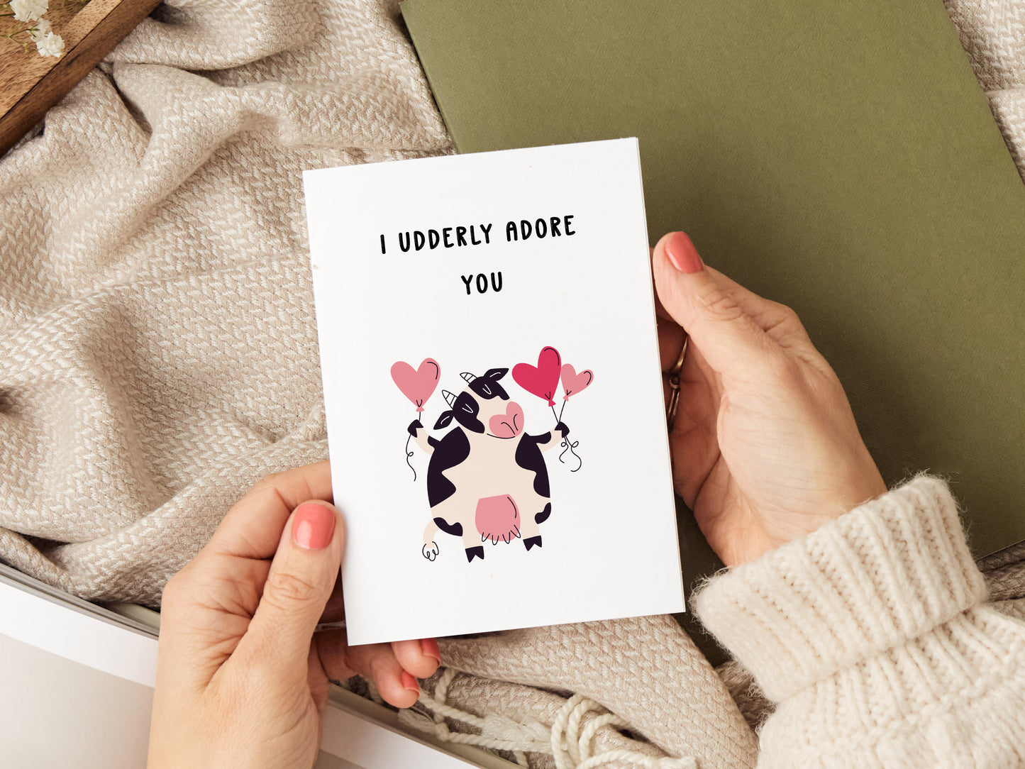 Anniversary card which reads 'I udderly adore you' with a illustration of a cow holding heart balloons.