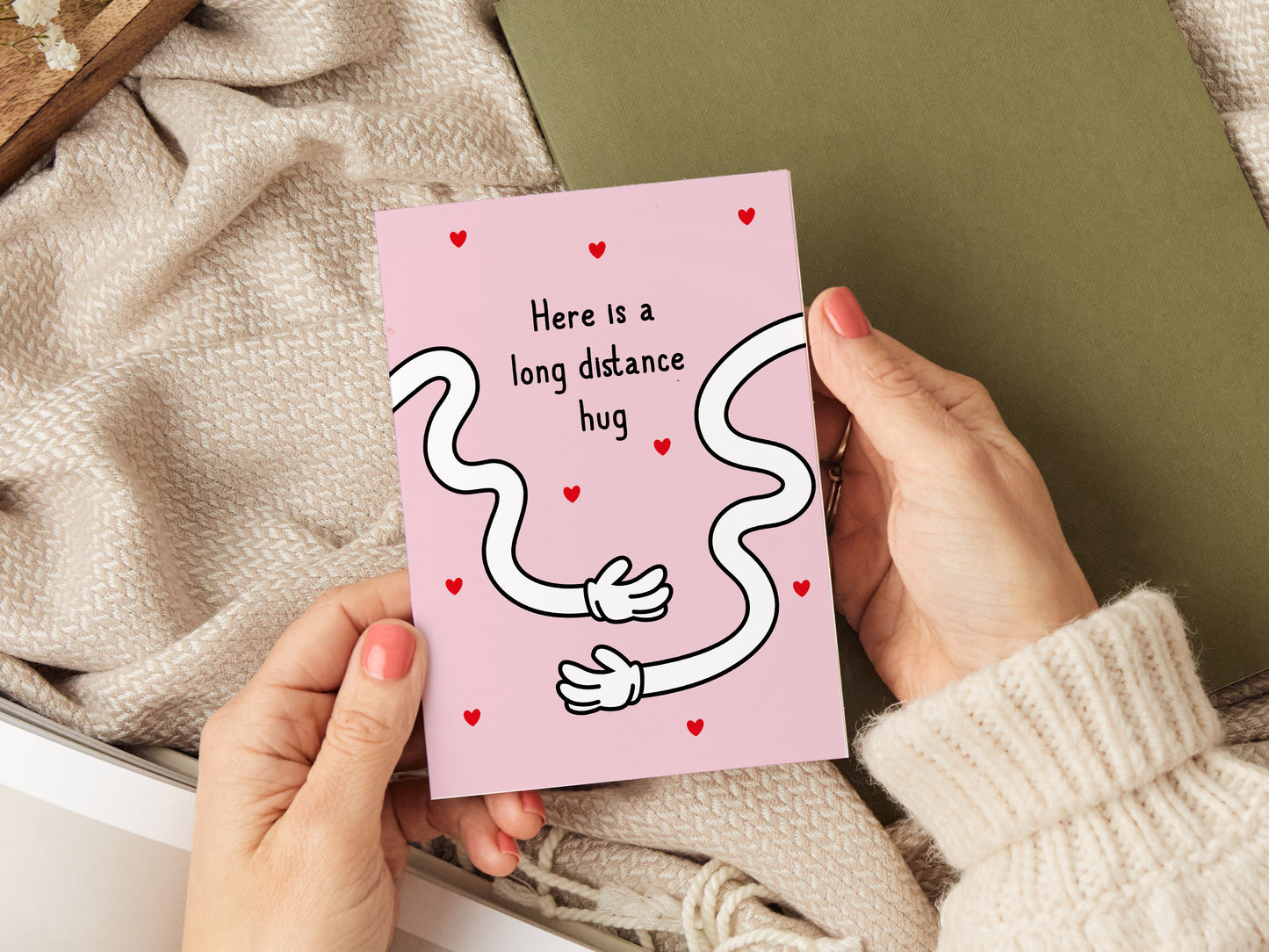 Greeting card which reads 'here is a long distance hug' with two long cartoon hands.