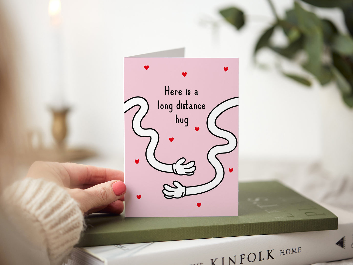 Greeting card which reads 'here is a long distance hug' with two long cartoon hands.