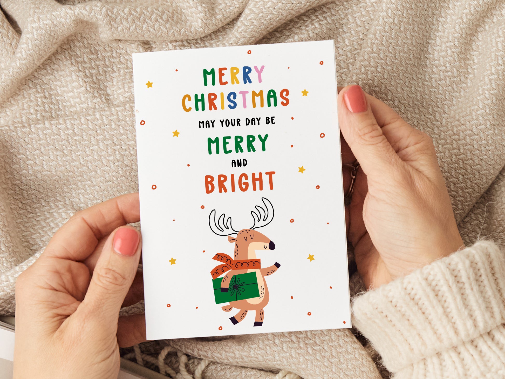 Christmas card which reads 'merry Christmas may your day be merry and bright' with an illustration of a reindeer holding a present.