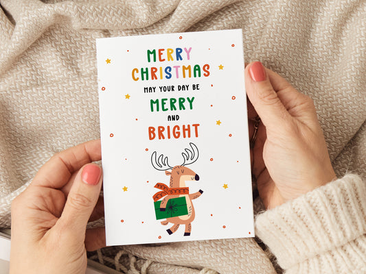 Christmas card which reads 'merry Christmas may your day be merry and bright' with an illustration of a reindeer holding a present.