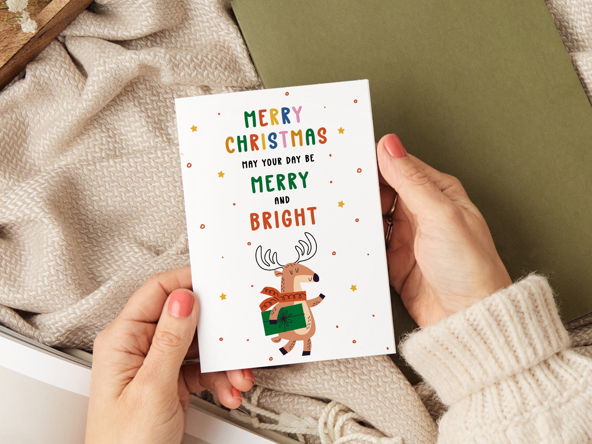 Christmas card which reads 'merry Christmas may your day be merry and bright' with an illustration of a reindeer holding a present.