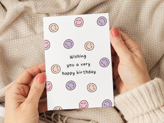 Birthday card which reads 'wishing you a very happy birthday' with lots of smiley faces.