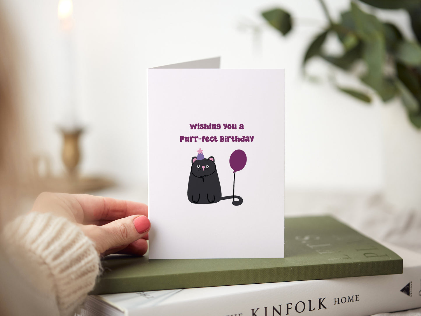 Birthday card which reads 'wishing you a pur-fect birthday' and has a illustration of a cat wearing a birthday hat and has a birthday balloon.